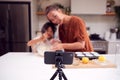 Asian Mother And Daughter Baking Cupcakes In Kitchen At Home Whilst On Vlogging On Mobile Phone Royalty Free Stock Photo