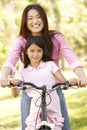Asian mother and daughter on bicycle in park Royalty Free Stock Photo