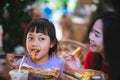 Asian mother and daughter eating sausage with happiness Royalty Free Stock Photo