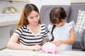 Asian mother and daughter putting coin in piggy bank, mom and kid with deposit account family together saving money for future, f Royalty Free Stock Photo