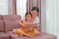 Asian mother and daughter reading a book on the sofa. Happy loving family at home Royalty Free Stock Photo