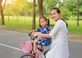 Asian mother and daughter riding bicycle together in park Royalty Free Stock Photo