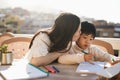 Asian mother doing homeworks with his little son outdoor on patio at home - Focus on child face Royalty Free Stock Photo