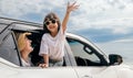 Asian mother father and children smiling sitting in compact white car looking out windows Royalty Free Stock Photo