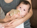 Asian mother feed milk her baby in bottle. Royalty Free Stock Photo