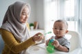 Asian Mother feeding her baby son with spoon Royalty Free Stock Photo
