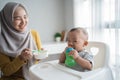 Asian Mother feeding her baby son with spoon