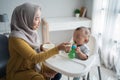 Asian Mother feeding her baby son with spoon Royalty Free Stock Photo