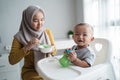 Asian Mother feeding her baby son with spoon Royalty Free Stock Photo