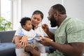 Asian mother feeding her 9 months old her cute little baby and African American helping for holding food plate At Home. Photo Royalty Free Stock Photo