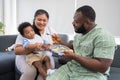 Asian mother feeding her 9 months old her cute little baby and African American helping for holding food plate At Home. Photo Royalty Free Stock Photo