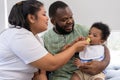 Asian mother feeding her 9 months old her cute little baby and African American helping for holding food plate At Home. Photo Royalty Free Stock Photo