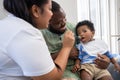 Asian mother feeding her 9 months old her cute little baby and African American helping for holding food plate At Home. Photo Royalty Free Stock Photo