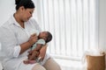 Asian mother feeding milk from bottle milk to her 1-month-old baby black skin newborn son Royalty Free Stock Photo