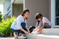 Asian mother help her daughter primary students in uniform to wearing their shoelace of shoes infront of home in the morning