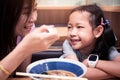Asian mother helped blow the food to cool for the daughter to eat noodle