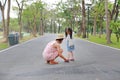 Asian mother helping her little daughter to put shoes on the road outdoor Royalty Free Stock Photo