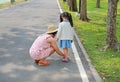 Asian mother helping her little daughter to put shoes on the road outdoor Royalty Free Stock Photo