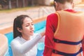 Asian mother helping her son to wear life jacket before playing in swimming pool, Selective focus Royalty Free Stock Photo