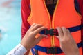 Asian mother helping her son to wear life jacket before playing in swimming pool, Selective focus Royalty Free Stock Photo