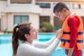 Asian mother helping her son to wear life jacket before playing in swimming pool, Selective focus Royalty Free Stock Photo