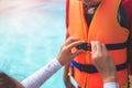 Asian mother helping her son to wear life jacket before playing in swimming pool, Selective focus Royalty Free Stock Photo