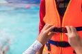 Asian mother helping her son to wear life jacket before playing in swimming pool, Selective focus Royalty Free Stock Photo