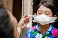 Asian mother helping her little son using face mask during pandemic