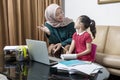 Asian mother helping little girl doing her homework with laptop at home Royalty Free Stock Photo