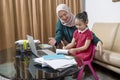 Asian mother helping little girl doing her homework with laptop at home Royalty Free Stock Photo