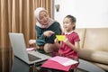 Asian mother helping little girl doing her homework with laptop at home Royalty Free Stock Photo