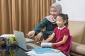 Asian mother helping little girl doing her homework with laptop at home Royalty Free Stock Photo