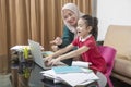 Asian mother helping little girl doing her homework with laptop at home Royalty Free Stock Photo