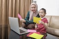 Asian mother helping little girl doing her homework with laptop at home Royalty Free Stock Photo