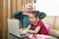 Asian mother helping little girl doing her homework with laptop at home Royalty Free Stock Photo