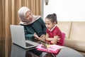 Asian mother helping little girl doing her homework with laptop at home Royalty Free Stock Photo