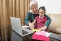 Asian mother helping little girl doing her homework with laptop at home Royalty Free Stock Photo