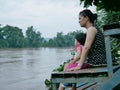 Asian mother and her little daughter by her side looking at murky muddy river after rainfall Royalty Free Stock Photo