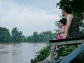 Asian mother and her little daughter by her side looking at murky muddy river after rainfall