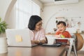 Asian mother and her son playing and laughing, Smiling Woman using laptop, Freelancer mom works from home with her cute child Royalty Free Stock Photo