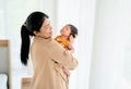 Asian mother hold sleeping newborn baby on her chest and stand in front of windows with white curtain with day light and she look Royalty Free Stock Photo