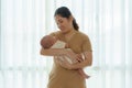 Asian mother is holding her newborn son in the bedroom at home, representing the love and bond between mother and son Royalty Free Stock Photo