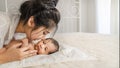 Asian mother holding and kissing her cute infant baby boy on bed Royalty Free Stock Photo