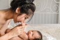 Asian mother holding and kissing her cute infant baby boy on bed Royalty Free Stock Photo