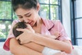 Asian mother holding a 1.5-month-old child leaning over her shoulder