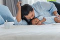 Asian mother kisses her 2-month-old newborn son, half-Thai-Nigerian, who is sleeping and lying on the bed. Royalty Free Stock Photo