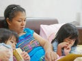 Asian mother opening a story tale book and spending time with her little baby girls, daughters, before their bedtime