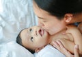 Asian Mother is playing and kissing her little baby boy on the bed Royalty Free Stock Photo