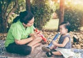 Asian mother playing plastic trumpet pipe with her daughter. Vintage tone. Royalty Free Stock Photo