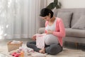 Asian mother preparing little clothes for new baby when sitting on the floor